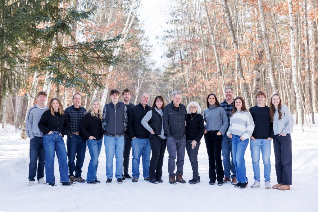 Winter family photography session in Spooner, Wisconsin, featuring a large family group posing together in a snowy forest setting.