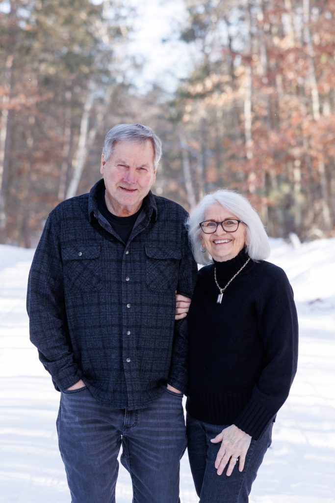 Couple posing together in a snowy forest during a winter family photography session in Spooner, Wisconsin.