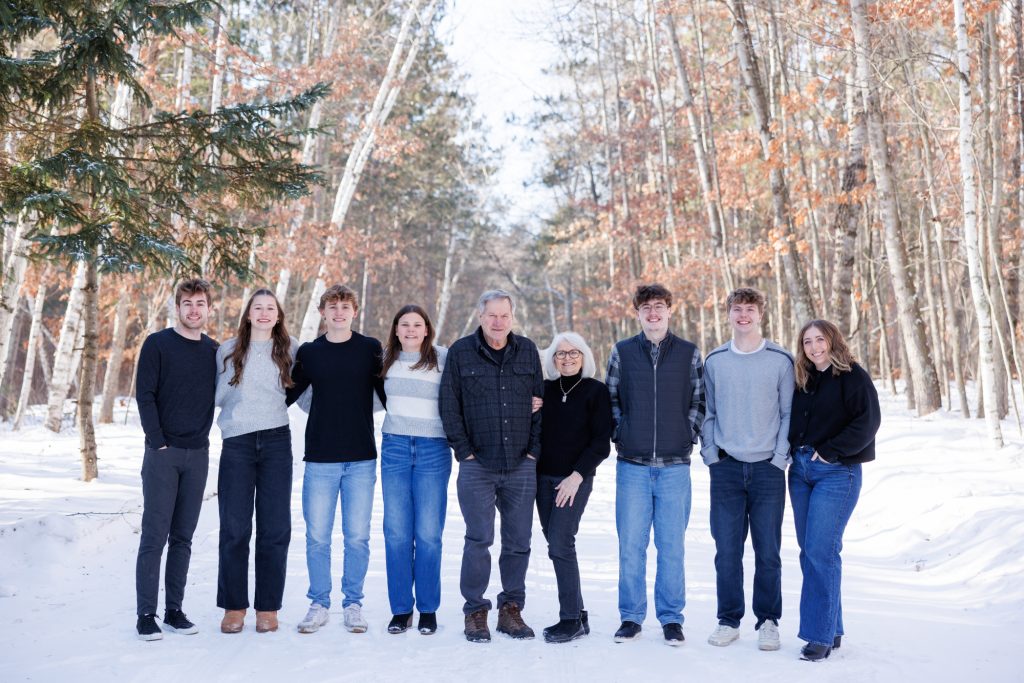 Winter family portrait in Spooner, Wisconsin, featuring the Laird family standing together in a snowy forest setting.