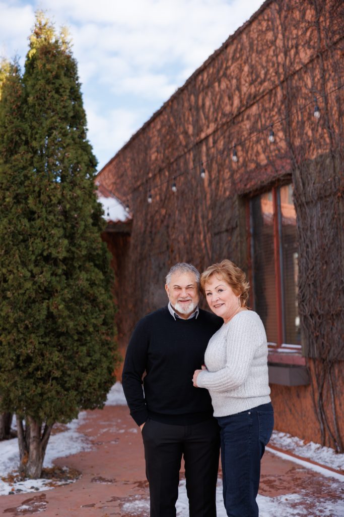 Jane and Bruce smiling together outdoors in Duluth, Minnesota, surrounded by snow and greenery, celebrating their winter photography session with Superior Sunset Studio.