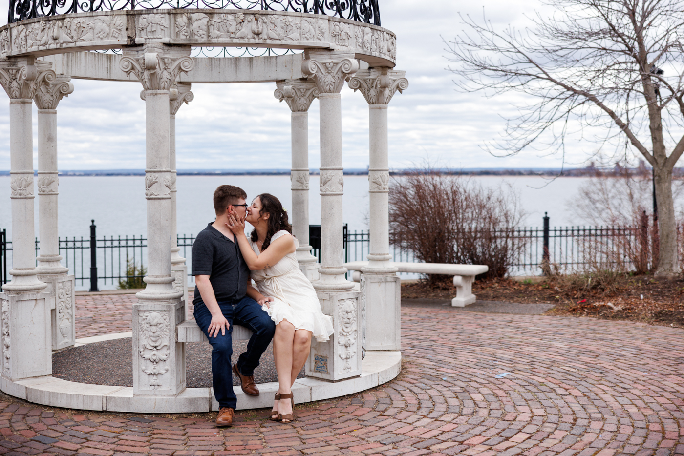 Couple sharing a romantic moment under a gazebo by the water, showcasing engagement photography in Duluth, Minnesota.