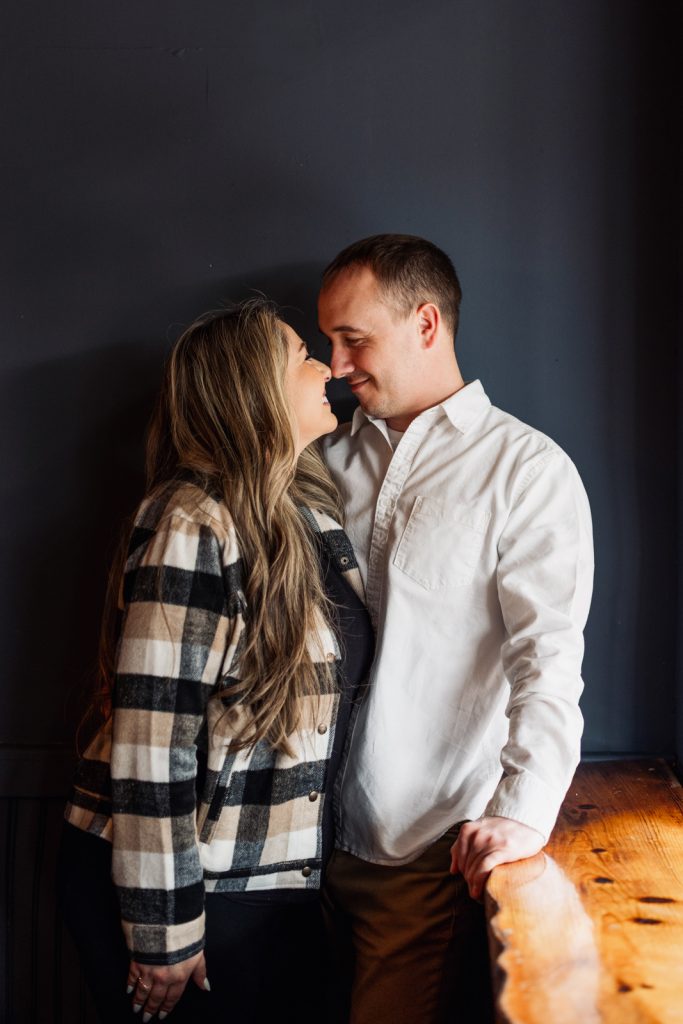 Bianca and Nick sharing an intimate moment during their engagement session at Superior Sunset Studio, showcasing love and connection against a dark backdrop.