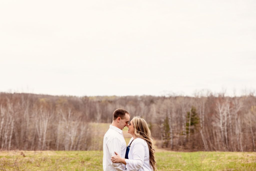 Bianca and Nick sharing a romantic moment during their engagement session in Hayward, WI, surrounded by a scenic natural landscape.