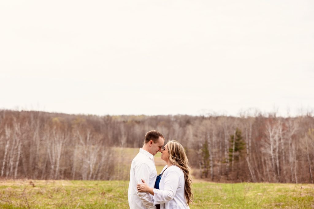 Bianca and Nick embracing in a scenic outdoor setting during their engagement session in Hayward, WI, showcasing their love amidst a natural backdrop.