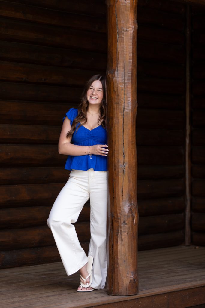 Julia's senior portrait session in Hayward, WI, leaning against a rustic wooden post.