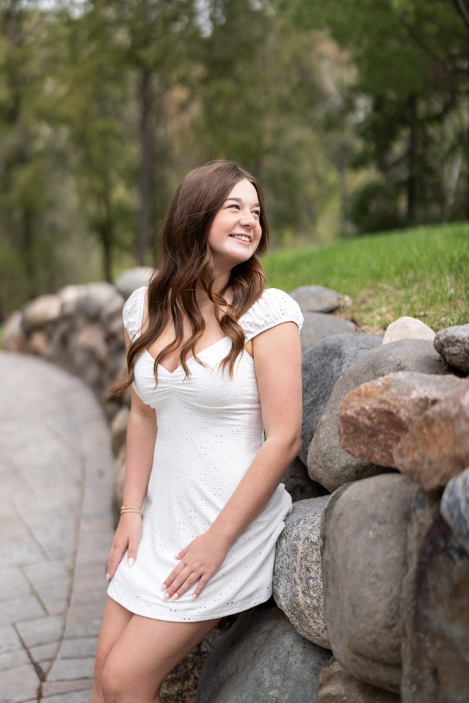Julia's senior portrait session in Hayward, WI, smiling and posing near a stone wall.
