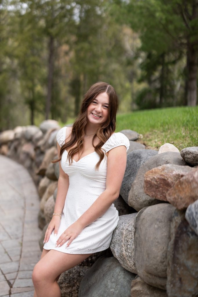 Julia's senior portrait session in Hayward, WI, showcasing a smiling graduate in a white dress.