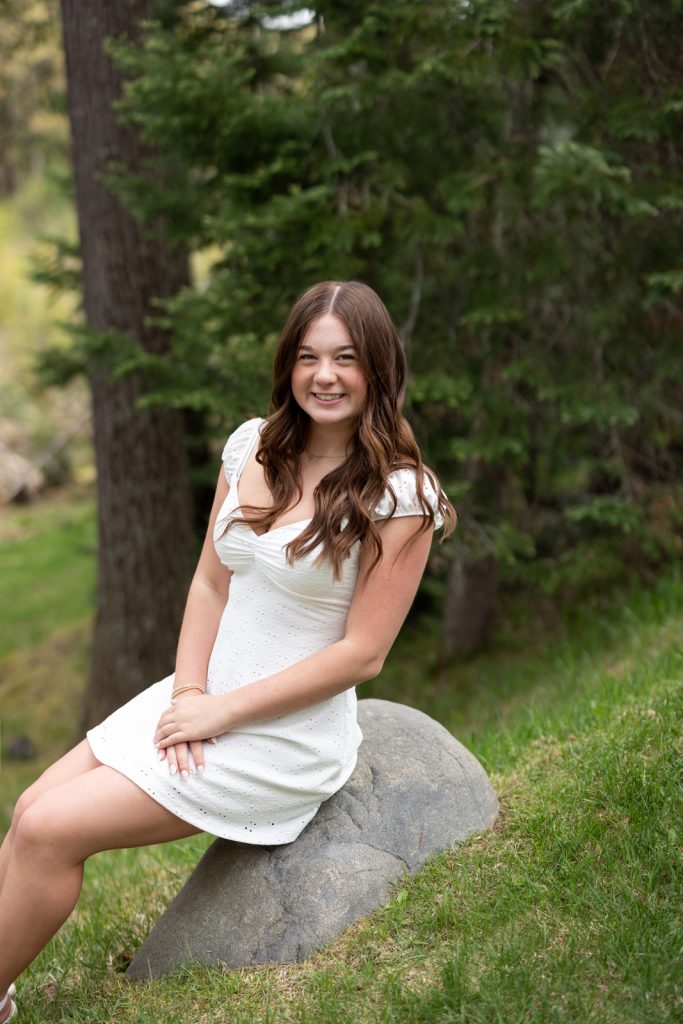 Julia's senior portrait session in Hayward, WI, smiling and seated on a rock in a