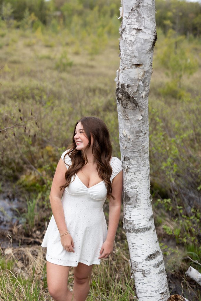 Julia's senior portrait session in Hayward, Wisconsin, leaning against a birch tree.