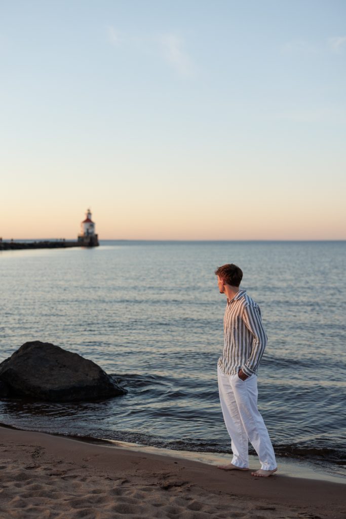 Jaymeson's senior portrait session on the beach in Duluth, Minnesota, with a lighthouse in the