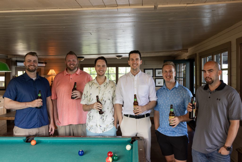 Group of groomsmen with beers at Stout’s Island Lodge wedding in Birchwood, Wisconsin.