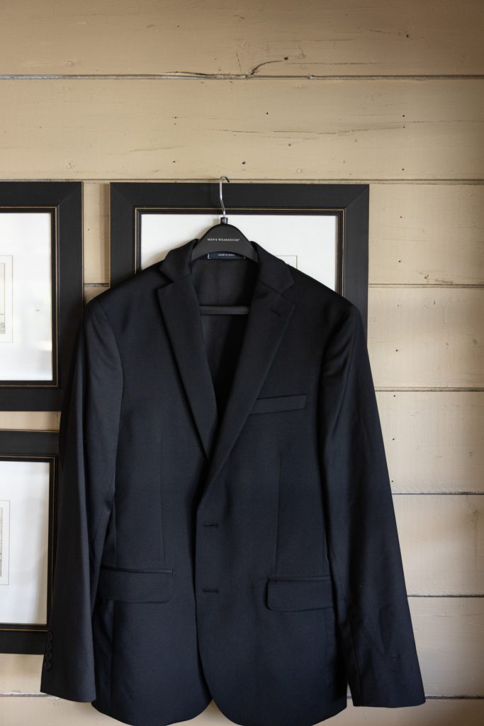 Groom's black suit jacket hanging on Stout’s Island, Wisconsin wedding details.