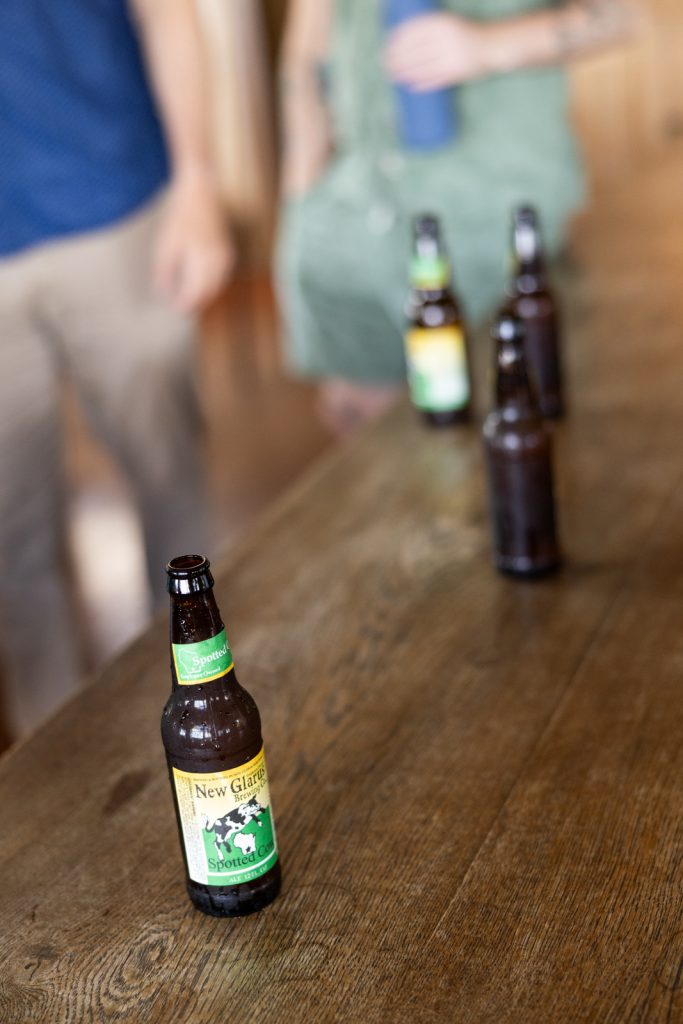 Stout’s Island wedding reception detail with Spotted Cow beer bottles on a wooden table