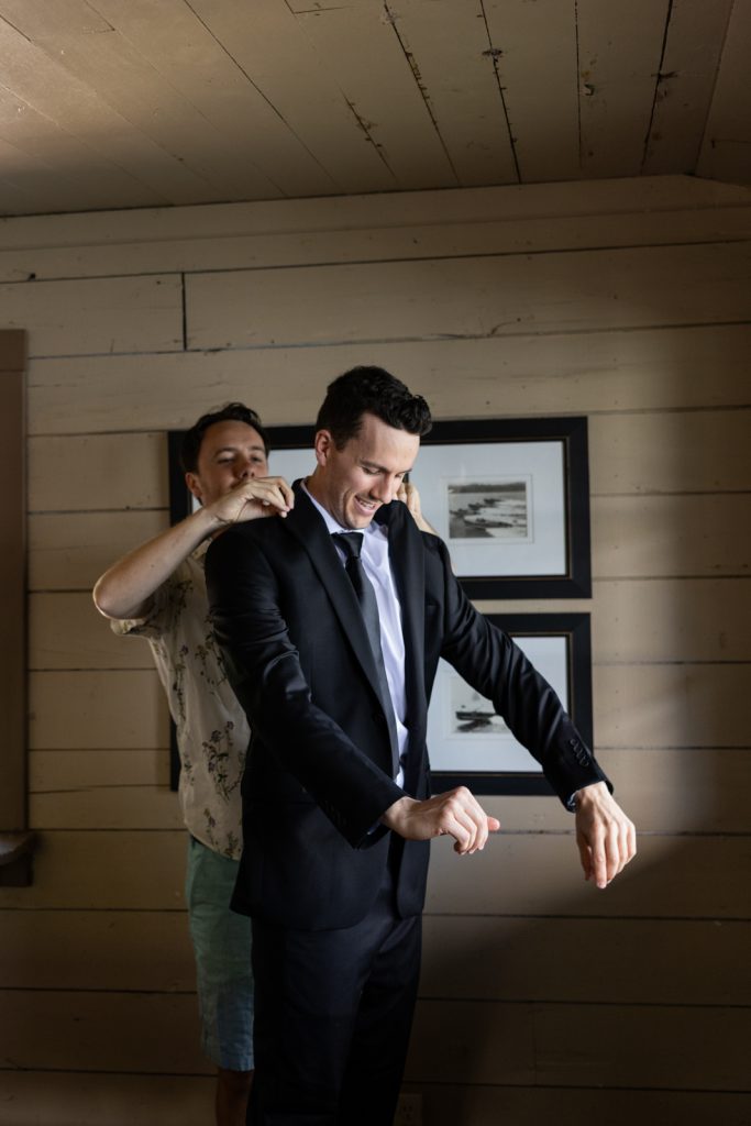 Groom getting ready in suit jacket at Stout’s Island wedding in Wisconsin.