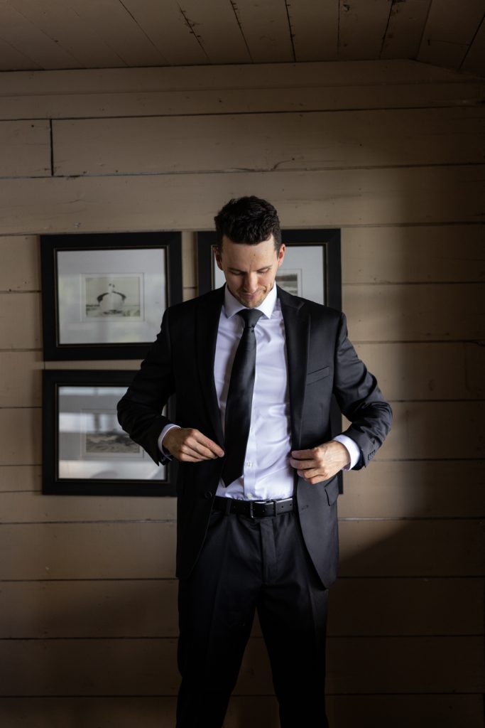 Brittany and Cole’s wedding groom adjusting his suit jacket at Stout’s Island Lodge in Wisconsin.