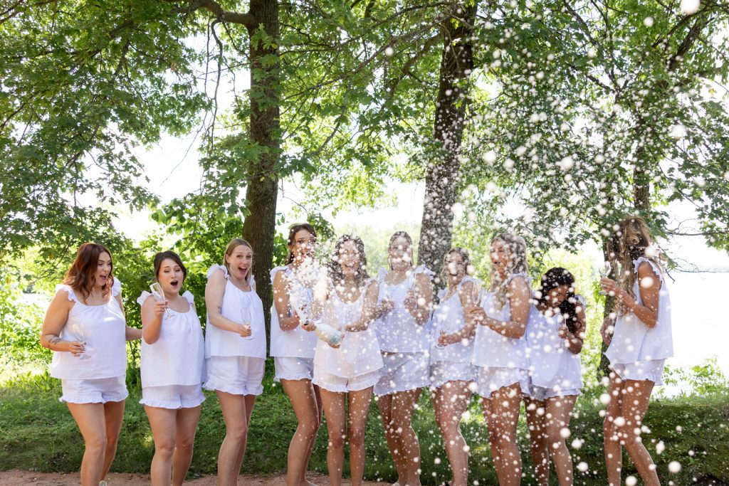 Brittany and Cole's wedding party celebrating with champagne on Stout’s Island, Wisconsin.