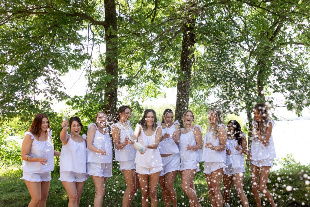 Brittany and her wedding party celebrating with champagne on Stout’s Island, Wisconsin.