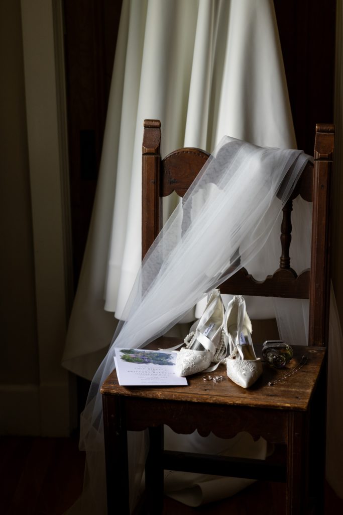 Bride's wedding dress, veil, and shoes on a wooden chair at Stout’s Island wedding in