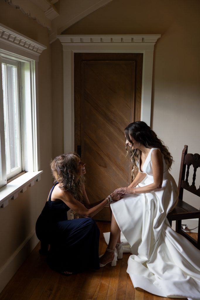Bride in wedding dress and bridesmaid preparing for Stout’s Island wedding ceremony.