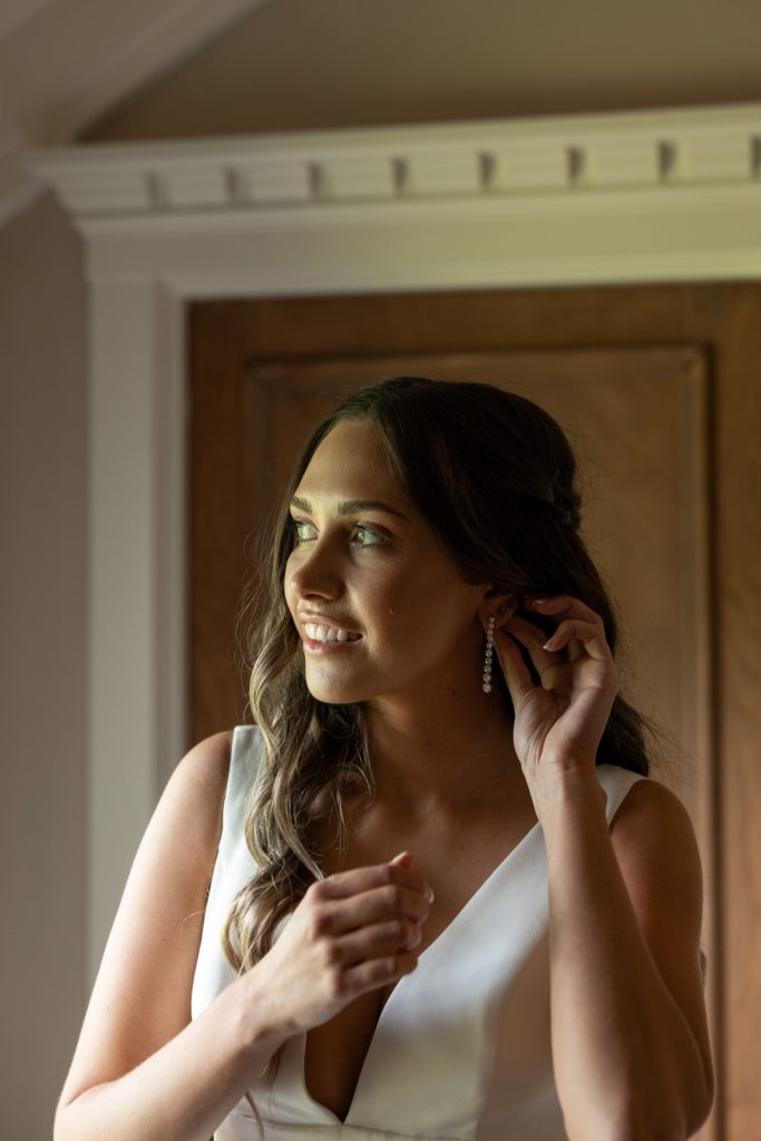 Bride Brittany getting ready on Stout’s Island, Wisconsin, wearing a wedding dress and earrings.
