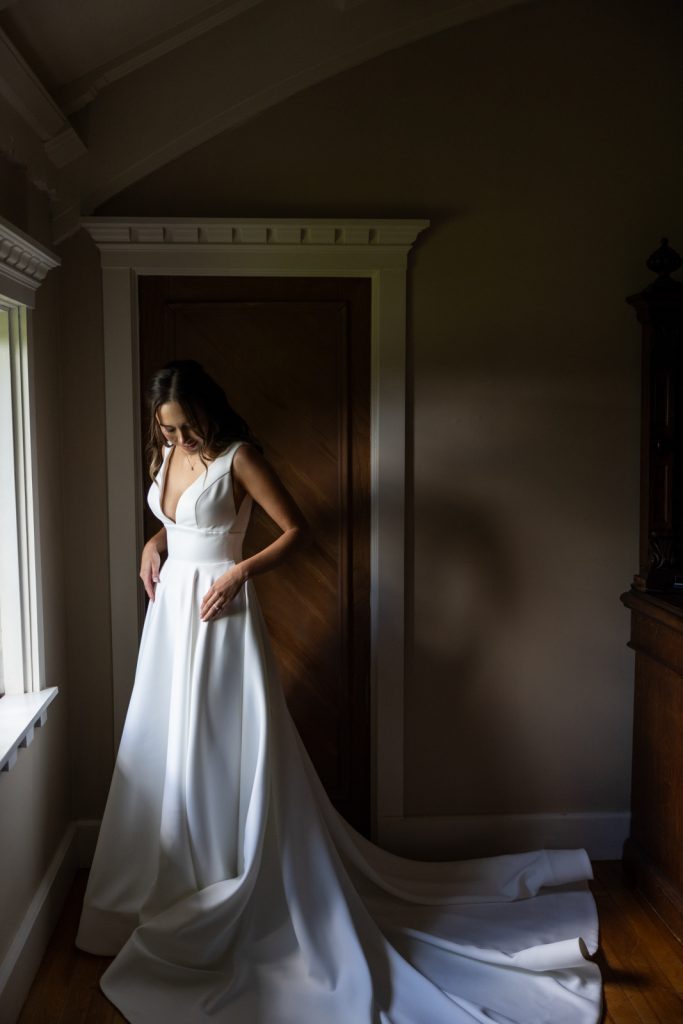 Bride in white gown near window at Stout’s Island Lodge wedding venue in Wisconsin