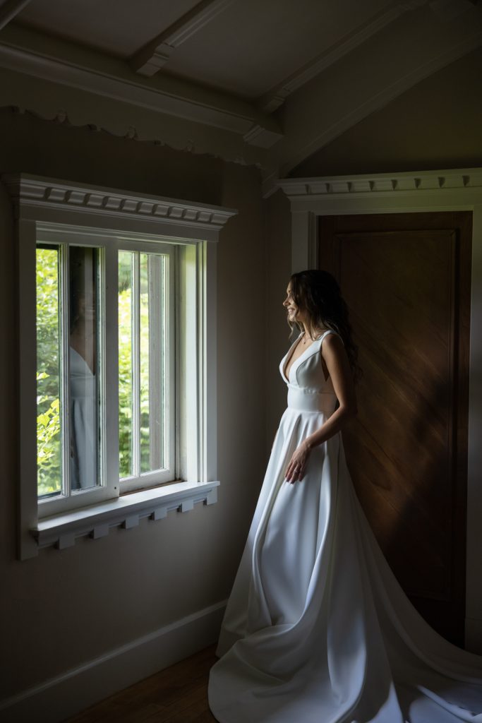 Bride in wedding dress looking out window at Stout’s Island resort.