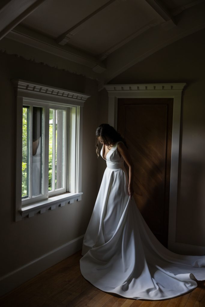 Bride in wedding dress near window at Stout’s Island Lodge, Birchwood, Wisconsin.