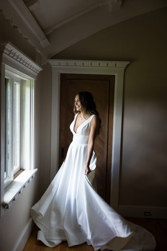 Bride in white wedding gown near window at Stout’s Island Lodge, Birchwood, Wisconsin.