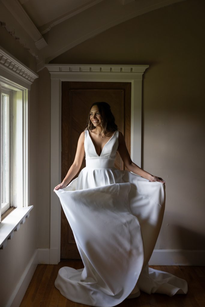 Bride in wedding dress posing near window at Stout’s Island Lodge wedding in Wisconsin