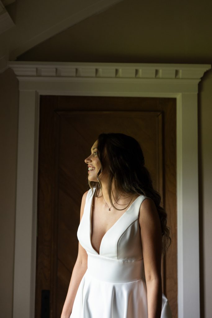 Bride in wedding dress looking out window at Stout’s Island Lodge.