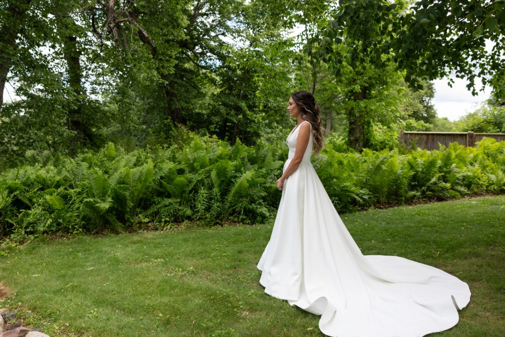 Bride in wedding dress on Stout’s Island, Birchwood, Wisconsin, surrounded by lush greenery and ferns.