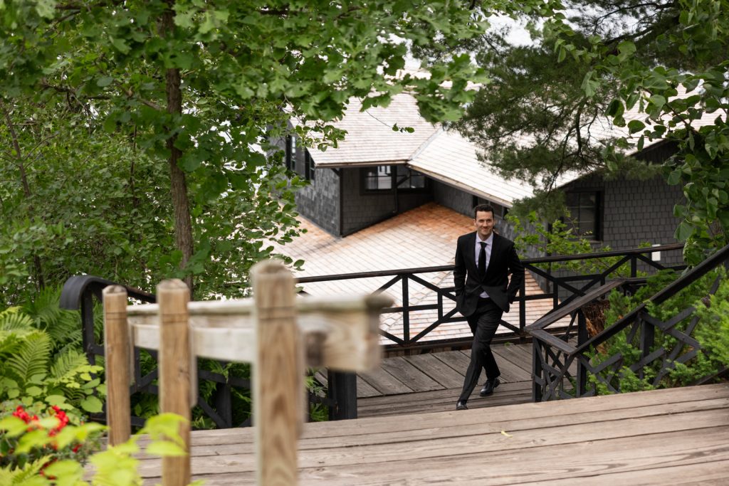 Groom in suit descending stairs at Stout’s Island Lodge wedding in Wisconsin.