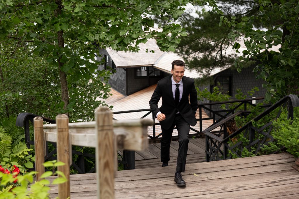 Brittany and Cole’s Stout’s Island wedding: groom descending wooden staircase on the island resort.