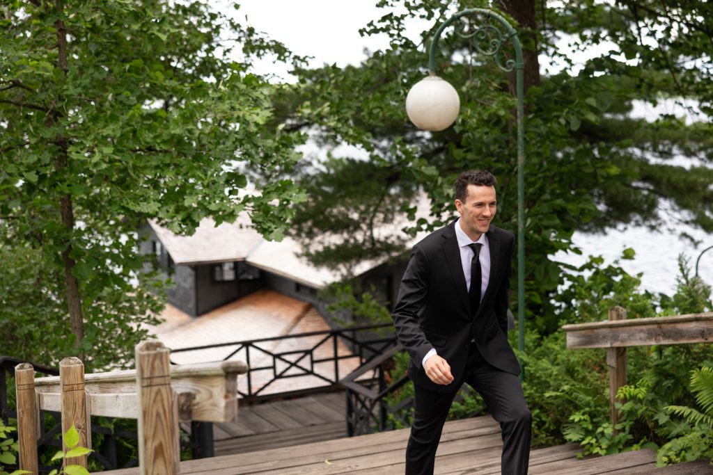 Groom in suit descending wooden stairs at Stout’s Island wedding in Birchwood, Wisconsin.