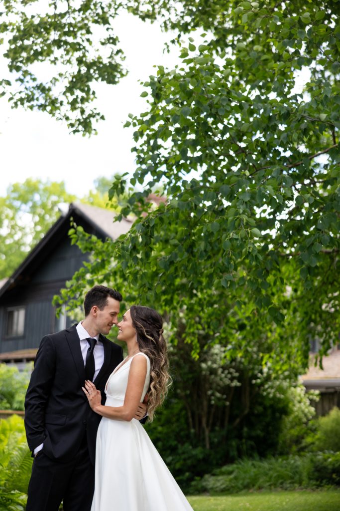 Brittany and Cole, wedding couple, embracing on Stout’s Island in Birchwood, Wisconsin, surrounded by lush