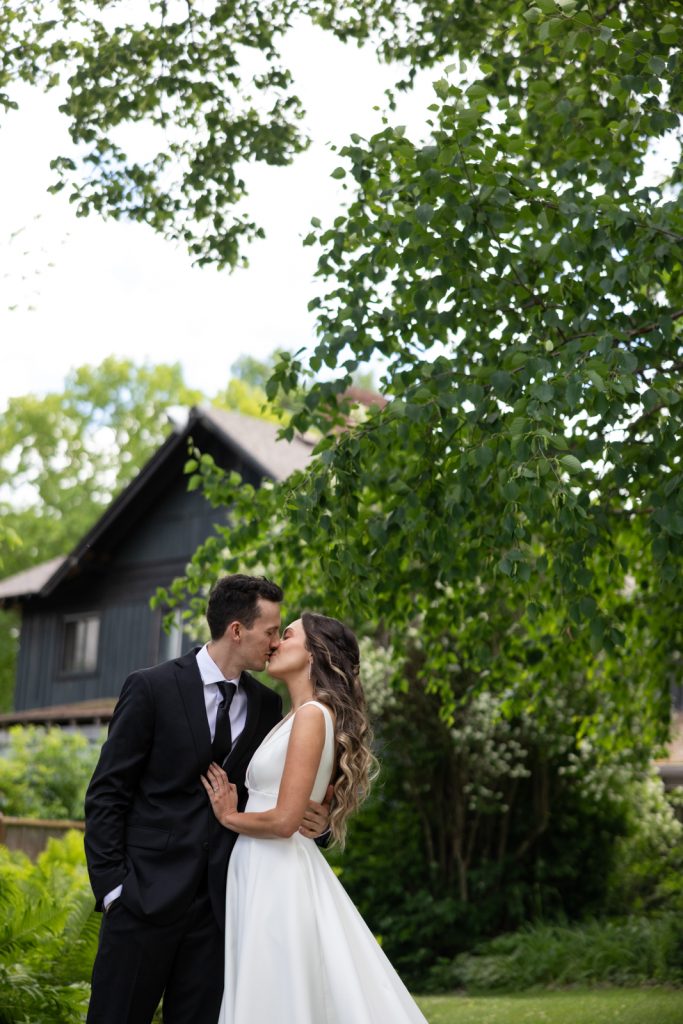 Brittany and Cole kissing during their Stout’s Island wedding in Birchwood, Wisconsin, surrounded by lush