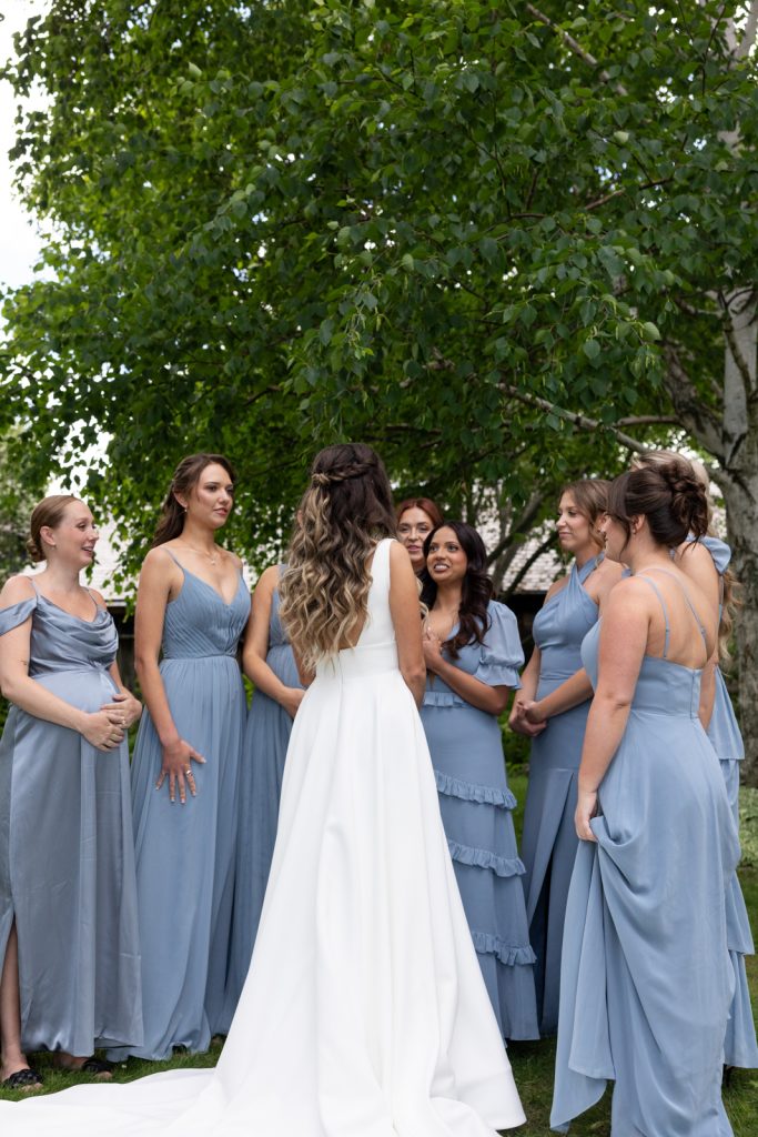 Bride in white dress with bridesmaids in blue dresses at Stout’s Island wedding.