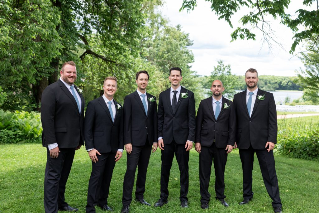 Brittany and Cole's Stout’s Island wedding party posing on the lawn and overlooking Red Cedar