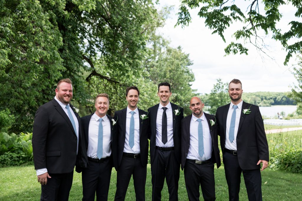 Brittany and Cole’s Stout’s Island wedding party posing in suits and ties near Red Cedar