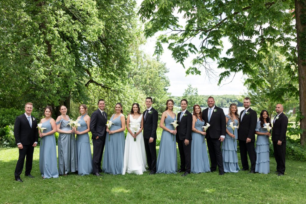 Brittany and Cole's Stout’s Island wedding party posing on the lawn and near Red Cedar