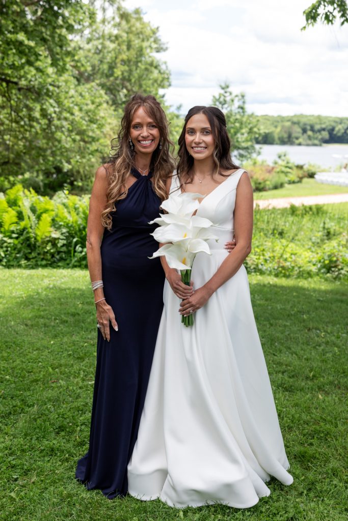 Bride and mother in wedding attire holding white lilies at Stout’s Island wedding in Wisconsin.