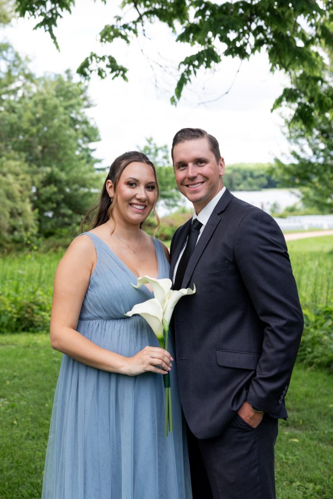 Brittany and Cole, the happy couple, posing with a white lily at their Stout’s Island