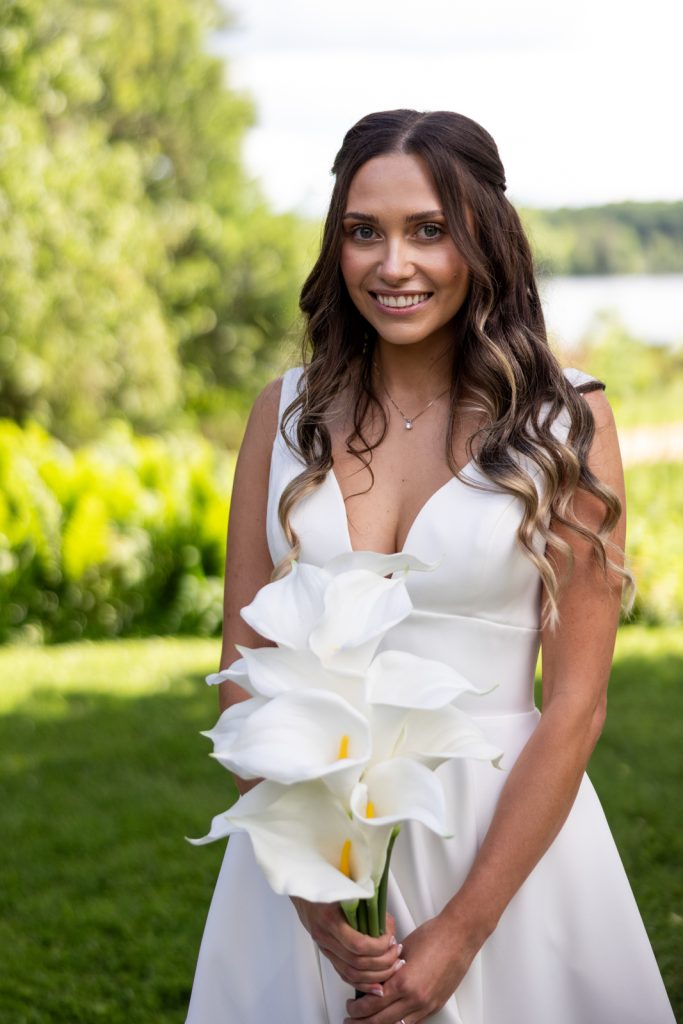 Brittany, the bride, holding a bouquet of white calla lilies at Stout’s Island wedding in