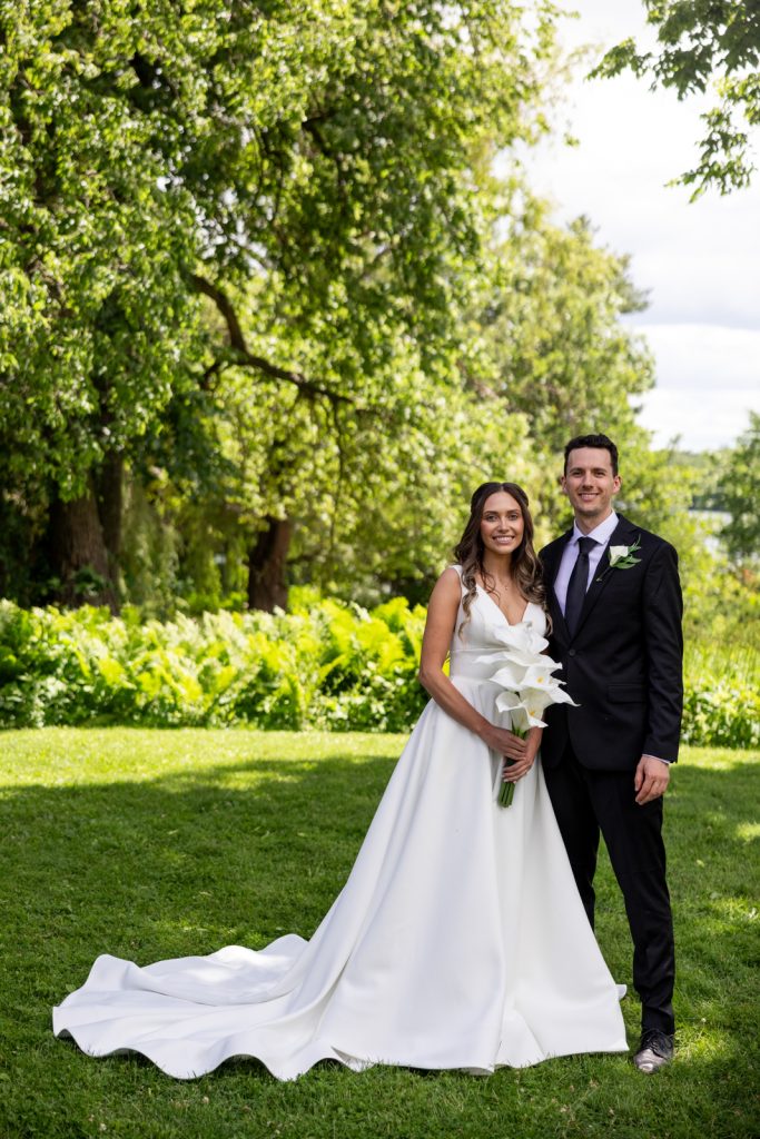 Brittany and Cole, the happy couple, posing with a bouquet of lilies at their Stout’s