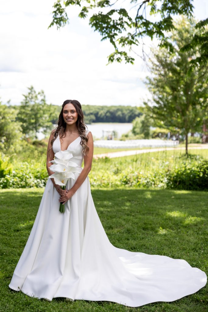 Bride in white wedding dress holding bouquet of white lilies on Stout’s Island, Wisconsin.
