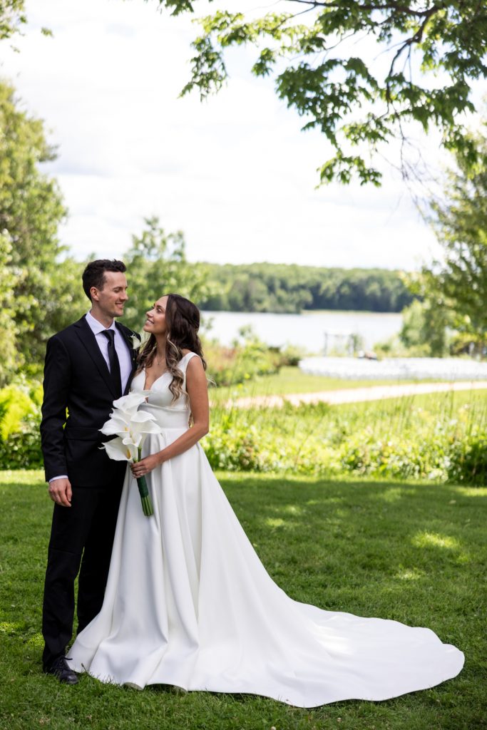 Brittany and Cole, the wedding couple, smiling and posing with a bouquet of white flowers