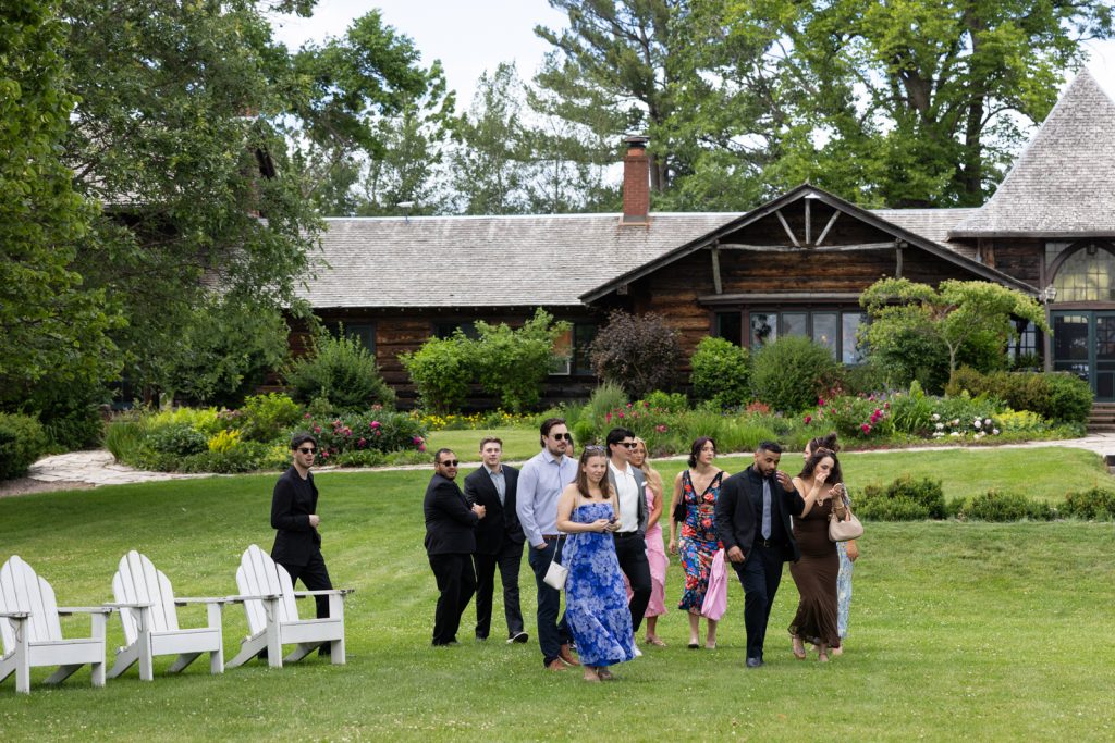Stout’s Island wedding party walking across lawn near boat house and lodge on Red Cedar