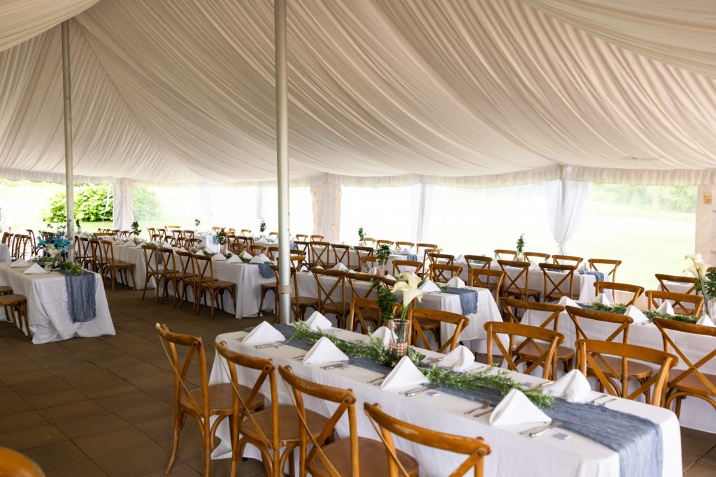 Wedding reception tables and chairs set inside a tent at Stout’s Island in Wisconsin.