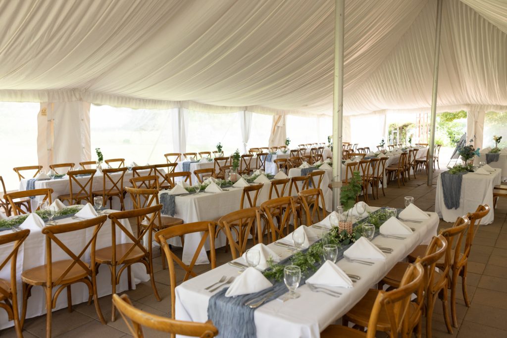 Elegant wedding reception tables and chairs inside a tent at Stout’s Island, Birchwood, Wisconsin.