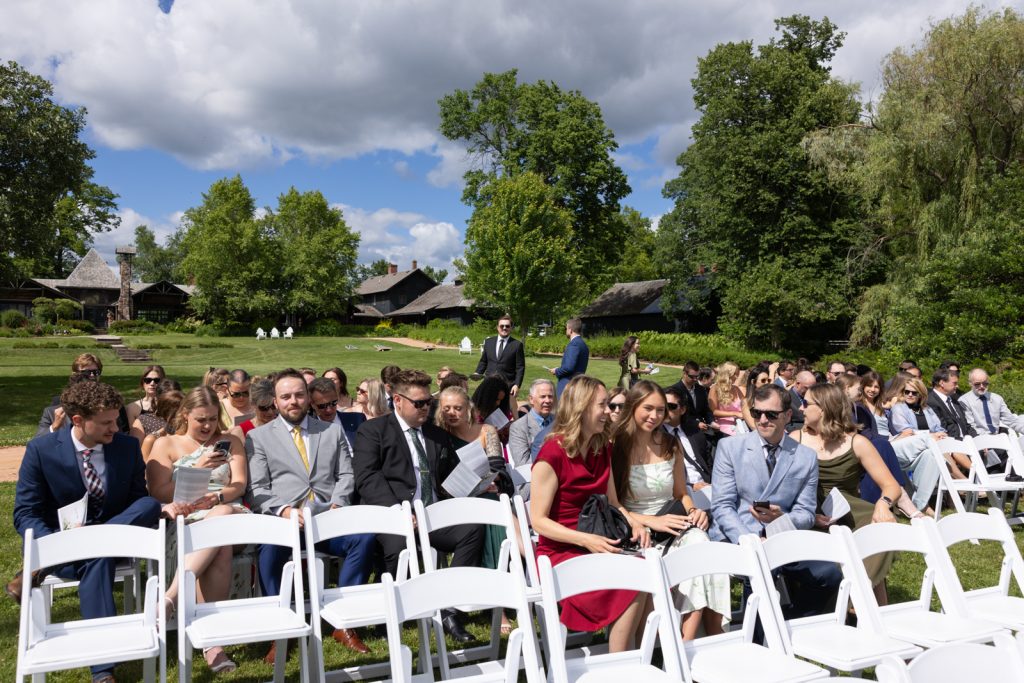 Brittany and Cole's Stout’s Island wedding ceremony with guests seated in white chairs and a